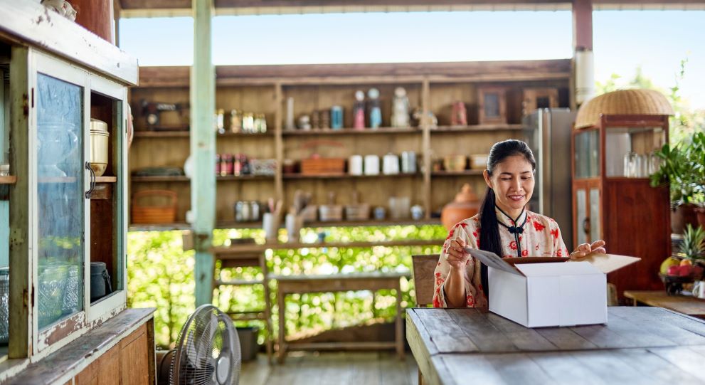 Asian woman opening a DHL package delivered to her