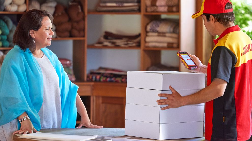 Woman business owner and DHL courier scanning packages