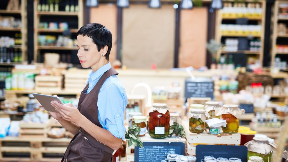 Woman business owner on tablet in her food store