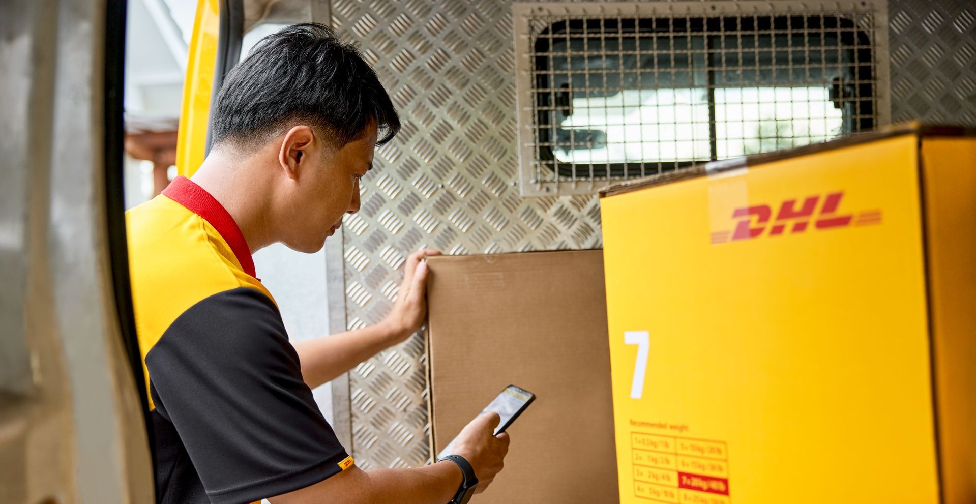 A DHL Express employee scans a DHL heavy parcel in his van.
