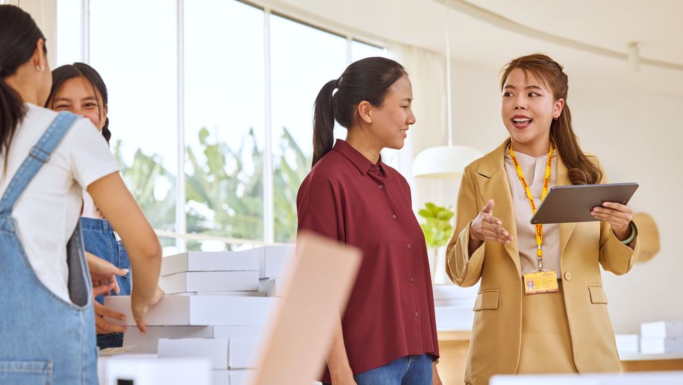  female dhl express employee presenting AI logistics solutions on her tablet to a business owner
