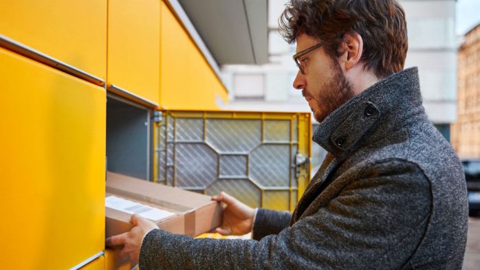 mann gibt paket in fach einer paketstation