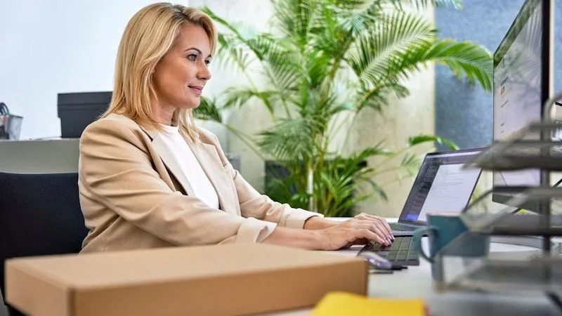 A woman works on a laptop in a modern office with plants