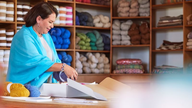 a female business owner packing yarn with enough protection for international shipment