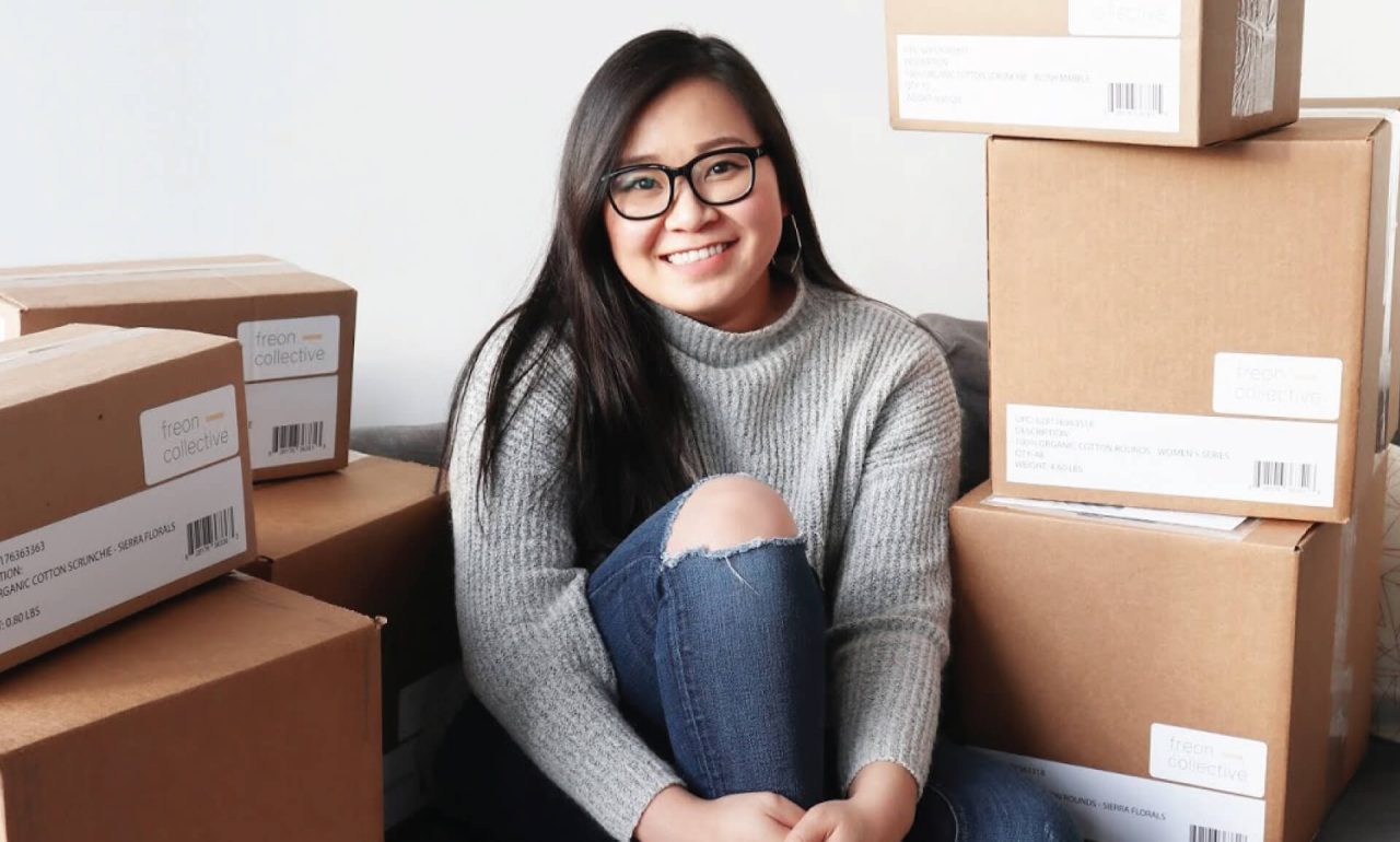 Nancy Mac sitting amongst boxes from her brand Freon Collective