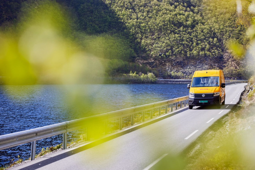 a DHL courier van drives beside a lake