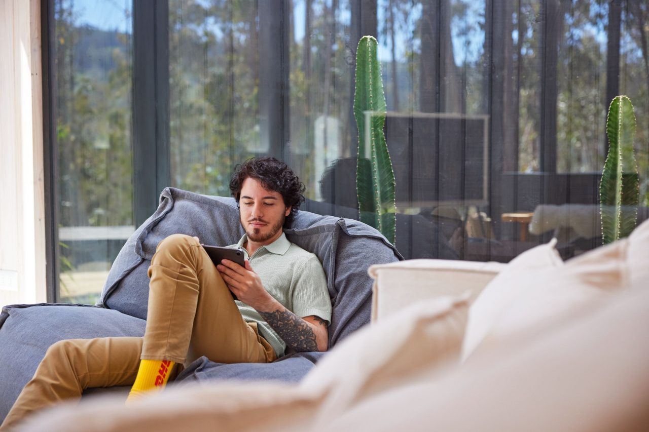 A man lies on a bean bag using an iPad.