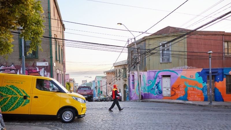 A DHL employee walks down the street with a parcel in hand.