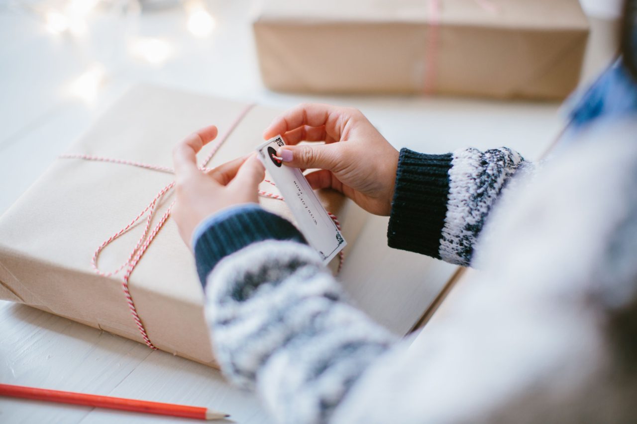 Close up of person's hands trying a note to a wrapped box 