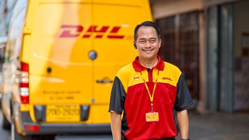 a dhl express courier standing in front of a delivery van