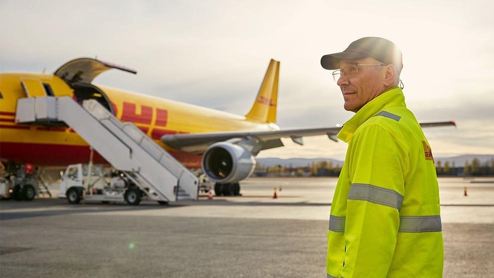 Man standing in front of DHL plane on runway