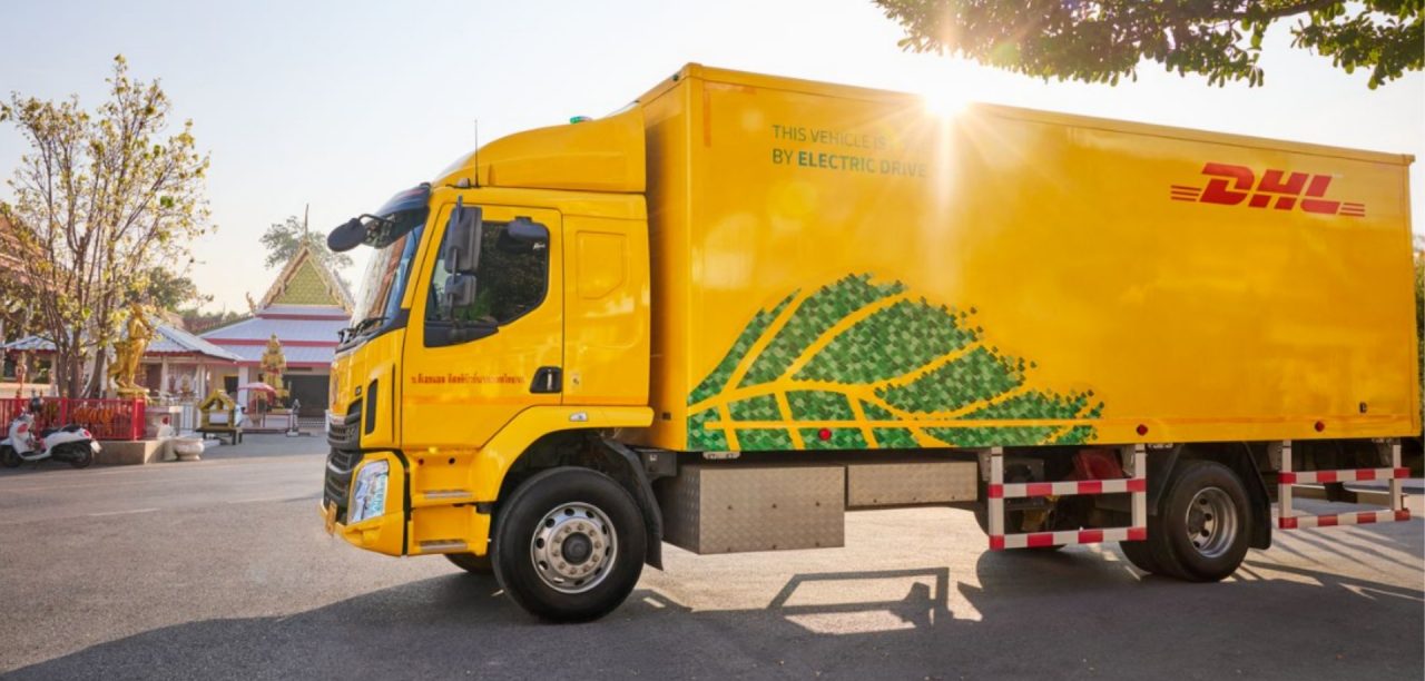 DHL electric truck parked in a parking lot surrounded by temples.