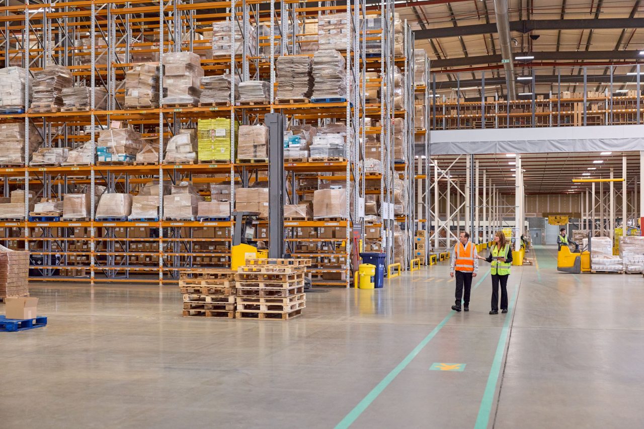 Two employees walk through a bonded warehouse storing imported goods. 